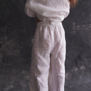 Pu&ograve; includere: Pantaloni bianchi in lino a gamba larga e vita elastica. I pantaloni sono realizzati in un tessuto leggero e traspirante, perfetti per il clima caldo.