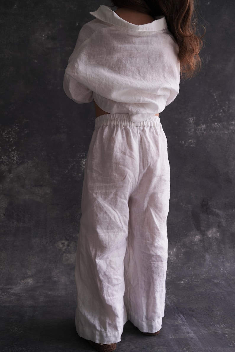 Pu&ograve; includere: Pantaloni bianchi in lino a gamba larga e vita elastica. I pantaloni sono realizzati in un tessuto leggero e traspirante, perfetti per il clima caldo.