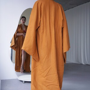 May include: A long, rust-colored robe with wide sleeves. The robe is made of a soft, flowing fabric and has a relaxed fit.