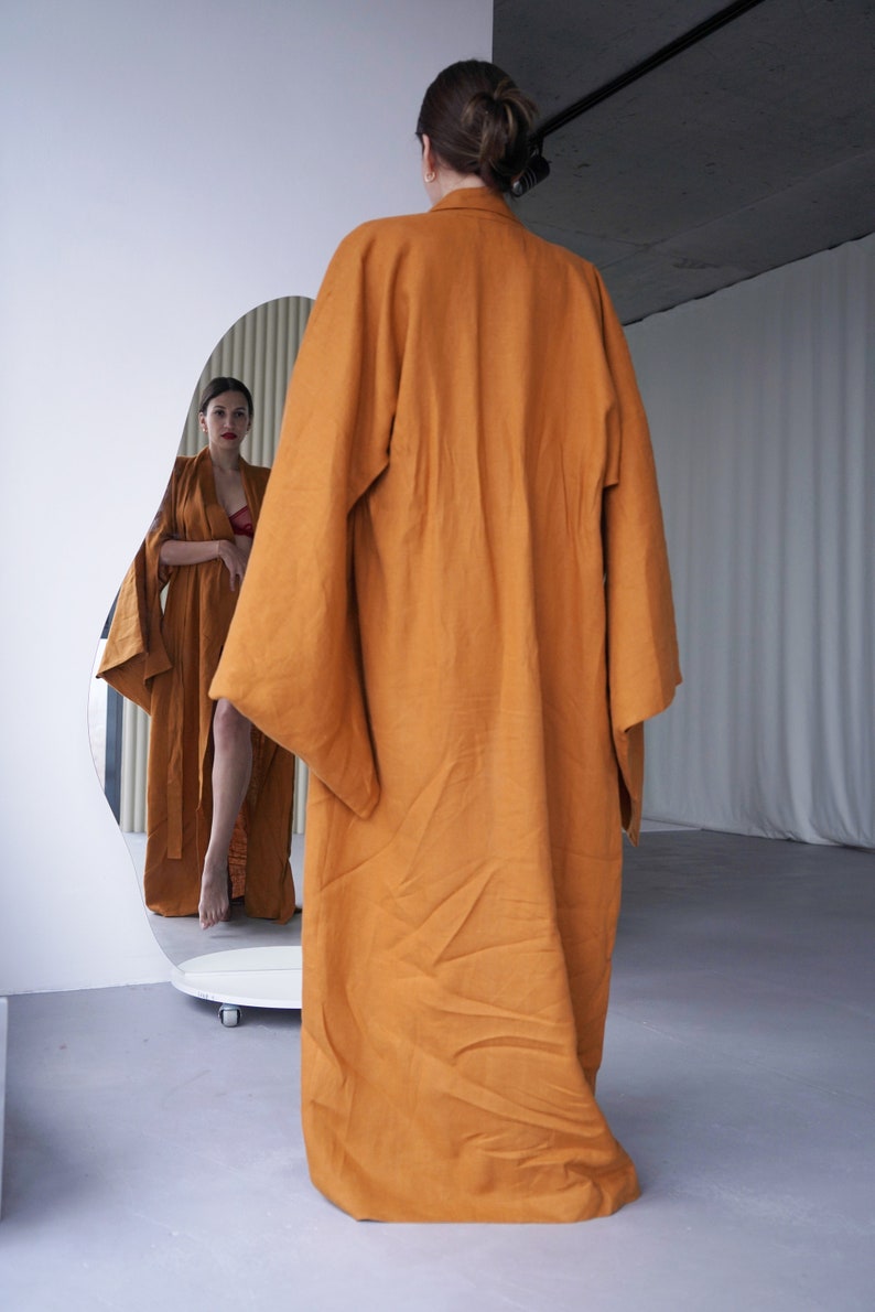 May include: A long, rust-colored robe with wide sleeves. The robe is made of a soft, flowing fabric and has a relaxed fit.