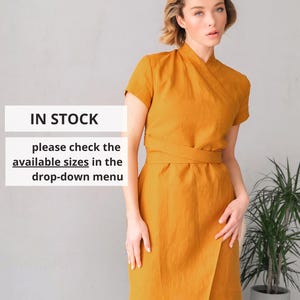 Peut inclure: Robe portefeuille moutarde à manches courtes et ceinture à la taille. La robe a un ourlet asymétrique. Le texte sur l'image indique "EN STOCK" et "veuillez vérifier les tailles disponibles dans le menu déroulant."