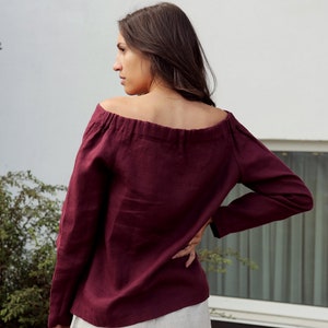 May include: A burgundy off-the-shoulder linen top with long sleeves.