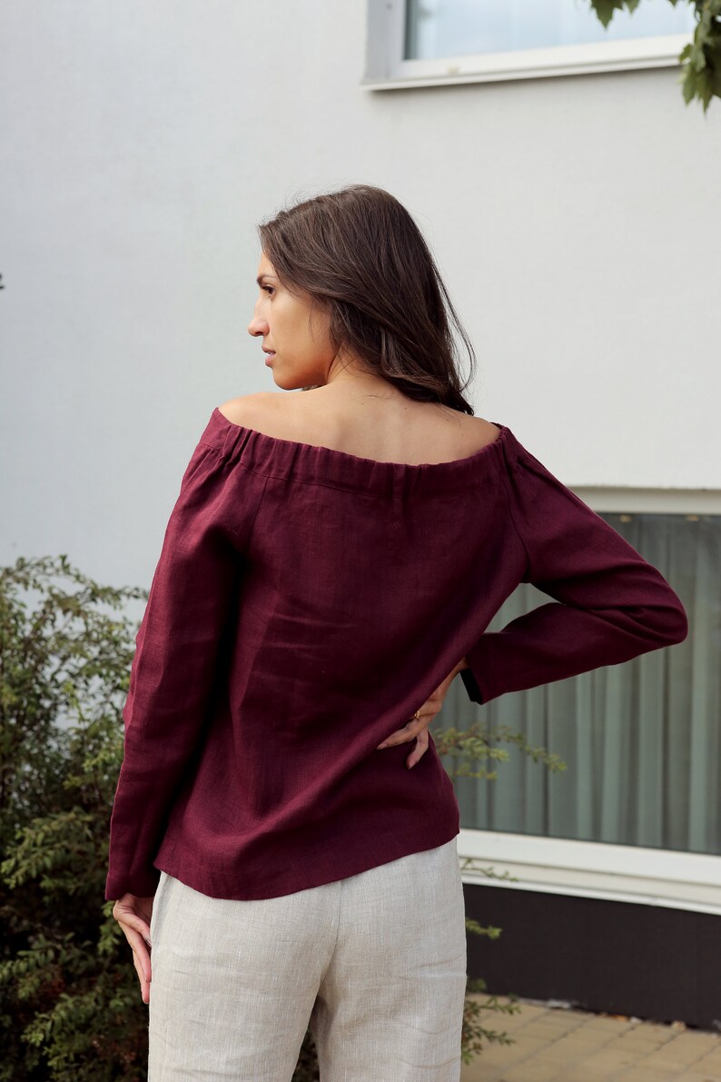 May include: A burgundy off-the-shoulder linen top with long sleeves.