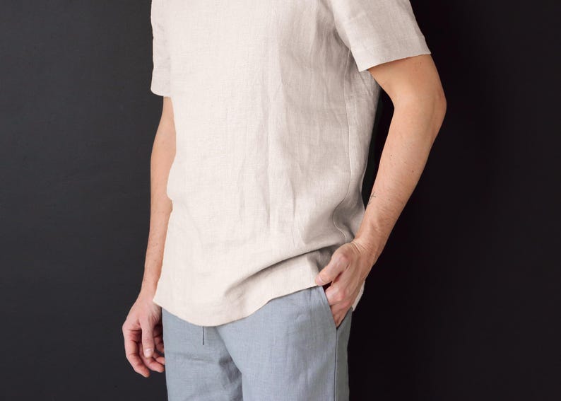 May include: A light beige linen t-shirt with short sleeves. The t-shirt is loose fitting and has a relaxed silhouette.
