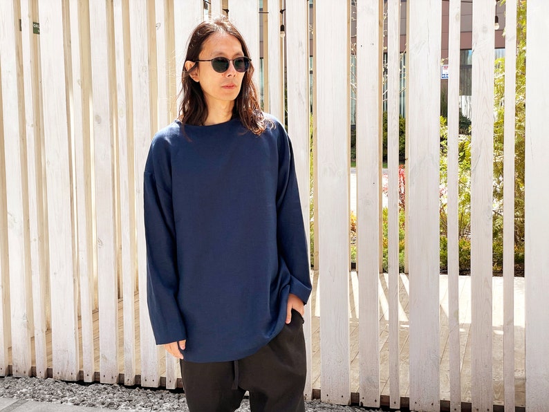 May include: A navy blue long-sleeved shirt with a relaxed fit. The shirt has a round neckline and is made of a soft, comfortable fabric.