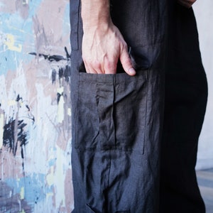 Pu&ograve; includere: Pantaloni in lino grigio scuro con ampie tasche cargo. I pantaloni hanno una vestibilit&agrave; rilassata e uno stile casual. Il tessuto sembra leggero e traspirante, adatto alle temperature pi&ugrave; calde. Una mano &egrave; in tasca.