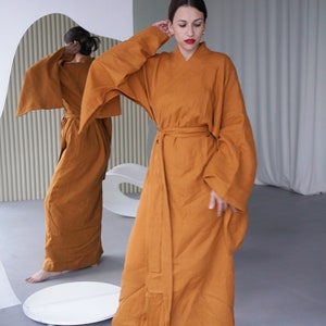 May include: A long, rust-colored robe with wide sleeves and a sash tied at the waist. The robe is made of a soft, flowing fabric.