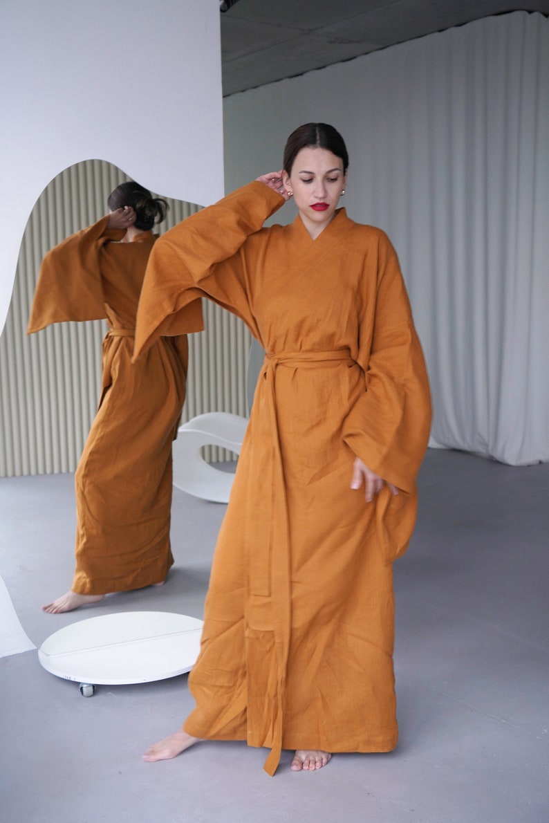 May include: A long, rust-colored robe with wide sleeves and a sash tied at the waist. The robe is made of a soft, flowing fabric.