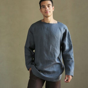 May include: A person wearing a long-sleeved, dark blue linen shirt with a relaxed fit and a round neckline. The shirt is tucked into brown pants.