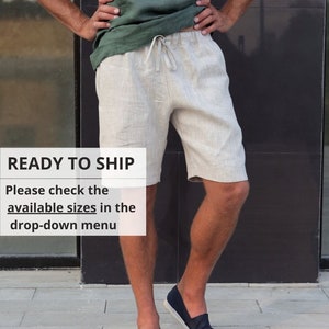 Può includere: Un uomo indossa pantaloncini di lino beige chiaro con vita a coulisse. Indossa una maglietta verde scuro e scarpe blu scuro da barca. Il testo "READY TO SHIP" e "Please check the available sizes in the drop-down menu" è visibile nell'immagine.