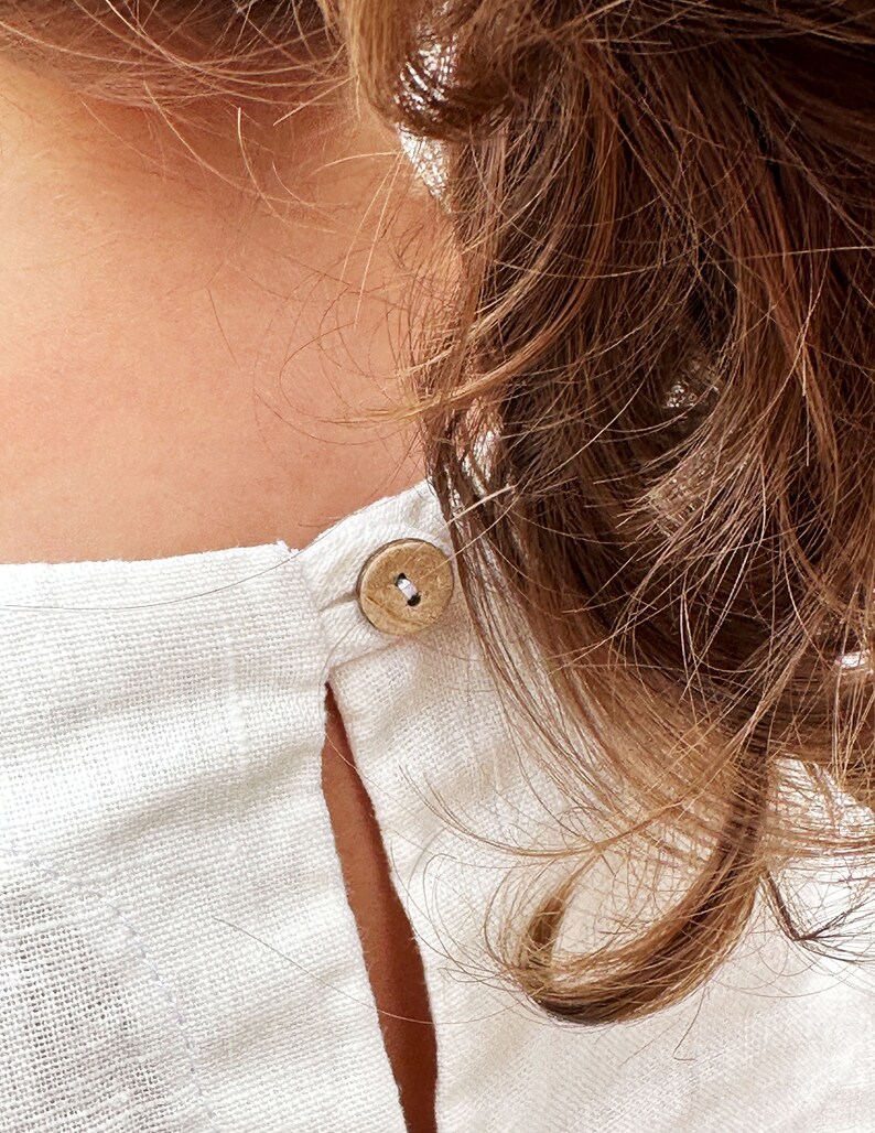May include: A white linen shirt with a wooden button at the back of the neck.