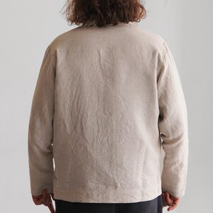 Puede incluir: Una camisa de lino beige de manga larga con cierre de botones.