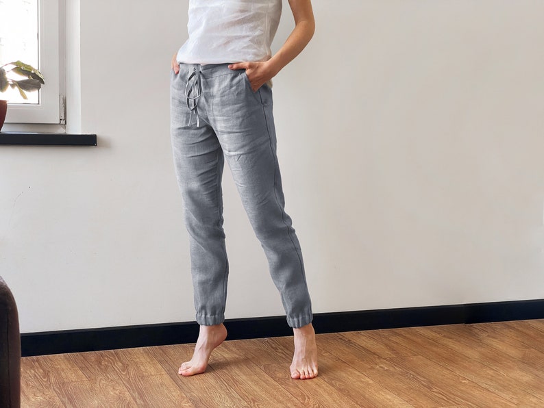 Op de afbeelding: Grijze linnen broek met een trekkoord in de taille en getailleerde pijpen. De broek is losjes gesneden en comfortabel.