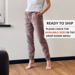 Può includere: Pantaloni in lino color malva con vita con coulisse e polsini elasticizzati. I pantaloni hanno tasche e una vestibilità rilassata. Il testo sull'immagine dice "READY TO SHIP" e "PLEASE CHECK THE AVAILABLE SIZES IN THE DROP-DOWN MENU".