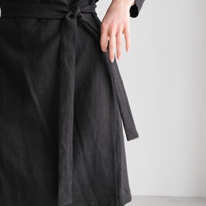 May include: A black wrap dress with a long sleeve and a self-tie belt.