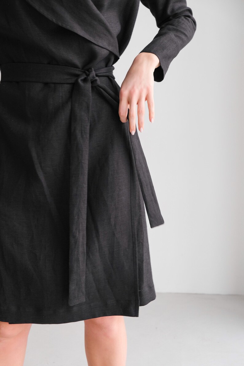 May include: A black wrap dress with a long sleeve and a self-tie belt.