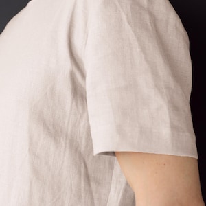 May include: A light beige linen t-shirt with short sleeves.
