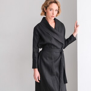 May include: A black linen wrap dress with a long sleeve and a tie belt. The dress has a deep V-neckline and a relaxed fit.