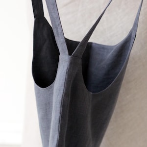 May include: A grey linen tote bag with two long straps. The straps are crossed at the top of the bag.