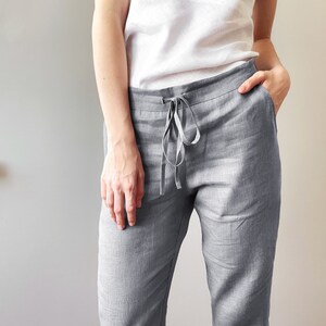 Op de afbeelding: Grijze linnen broek met een trekkoord. De broek heeft een ontspannen pasvorm en is gemaakt van een lichtgewicht stof.