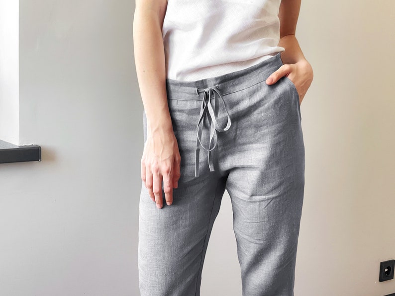 Op de afbeelding: Grijze linnen broek met een trekkoord. De broek heeft een ontspannen pasvorm en is gemaakt van een lichtgewicht stof.