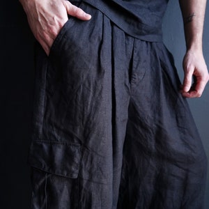 Pu&ograve; includere: Pantaloni in lino color carbone scuro con vestibilit&agrave; rilassata. I pantaloni presentano una tasca cargo sulla gamba sinistra e pieghe in vita. Il modello indossa una camicia abbinata color carbone scuro.