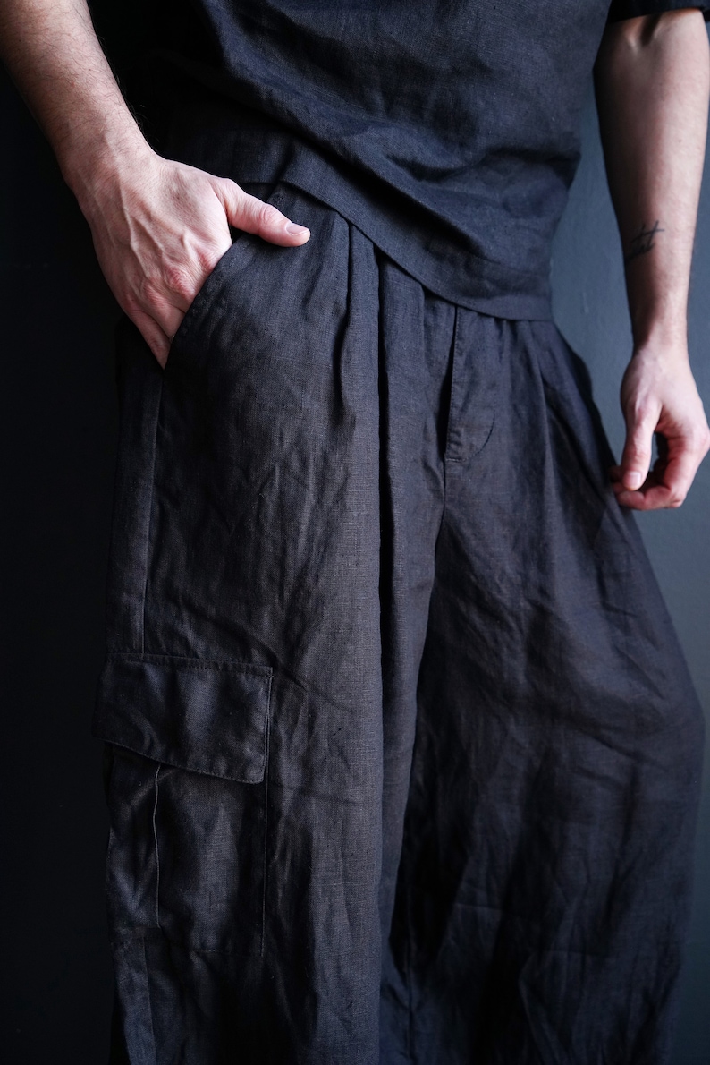 Pu&ograve; includere: Pantaloni in lino color carbone scuro con vestibilit&agrave; rilassata. I pantaloni presentano una tasca cargo sulla gamba sinistra e pieghe in vita. Il modello indossa una camicia abbinata color carbone scuro.