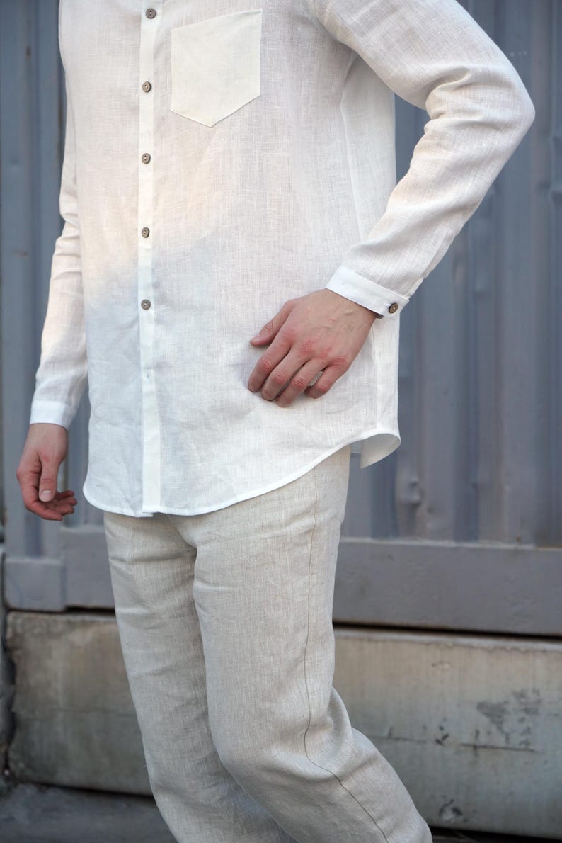 Pu&ograve; includere: Una camicia bianca di lino con colletto abbottonato e una tasca sul petto. La camicia &egrave; a maniche lunghe e ha una vestibilit&agrave; rilassata. Il modello indossa la camicia con pantaloni bianchi di lino.