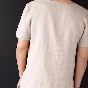 May include: A light beige linen shirt with a scoop neck and short sleeves.