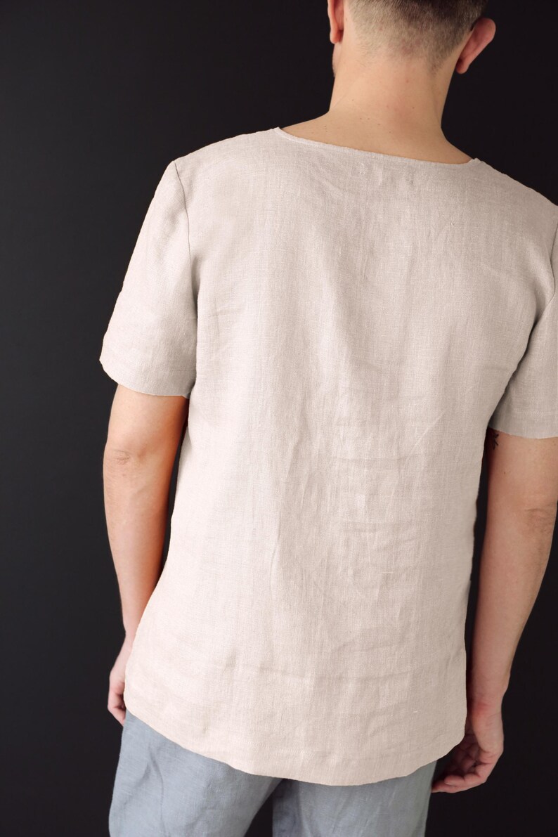 May include: A light beige linen shirt with a scoop neck and short sleeves.
