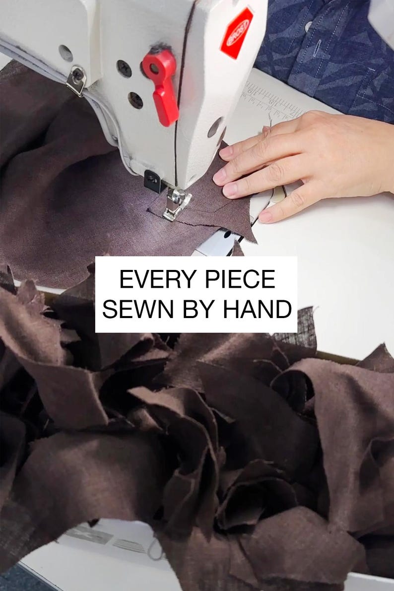 Peut inclure: Une machine &agrave; coudre cousant du tissu marron. L'image contient le texte &laquo; EVERY PIECE SEWN BY HAND &raquo;. La couture &agrave; la main est mise en &eacute;vidence, soulignant le savoir-faire et l'attention port&eacute;e aux d&eacute;tails du produit.