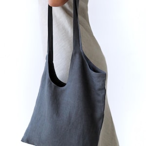 May include: A dark grey linen tote bag with long straps. The bag is large enough to carry groceries or other items.