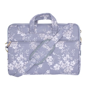 May include: A grey laptop bag with a white floral pattern and a grey adjustable shoulder strap. The bag has a zipper closure and a gold zipper pull.