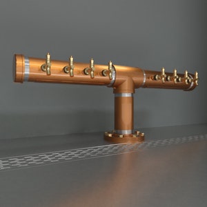 May include: A copper beer tap system with multiple spouts and a base. The tap system is mounted on a stainless steel surface.