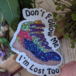 Puede incluir: Una pegatina blanca con una bota de senderismo azul brillante y el texto "No me sigas, también estoy perdido".