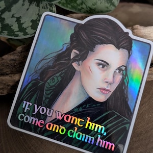 May include: Holographic sticker featuring a portrait of a woman with long dark hair and a green and black patterned garment. The sticker has the text "If you want him, come and claim him" in a rainbow gradient.