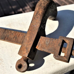 May include: A rusty metal clamp with a screw and a handle. The clamp has a ruler on each side.