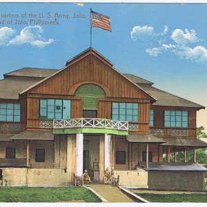 May include: A postcard depicting a wooden building with a porch and a flagpole with an American flag. The building is surrounded by grass and trees. The text on the postcard reads: "A 171 - Headquarters of the U. S. Army, Jolo, Island of Jolo, Philippines."