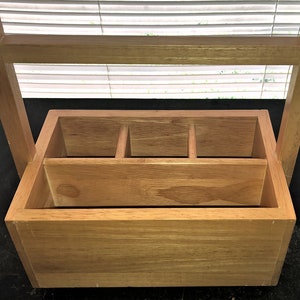 May include: A wooden cutlery organizer with a handle. The organizer has four compartments and is made of natural wood.