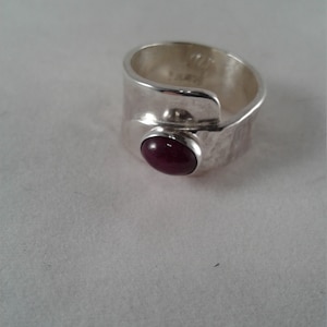 Puede incluir: Un anillo de plata con acabado martillado y una piedra preciosa cabuj&oacute;n de color morado oscuro.