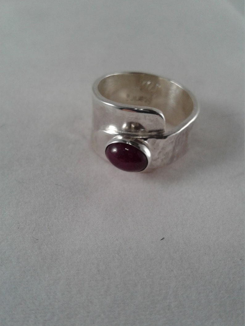 Puede incluir: Un anillo de plata con acabado martillado y una piedra preciosa cabuj&oacute;n de color morado oscuro.