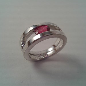 May include: A silver ring with a red gemstone set in a double band design.