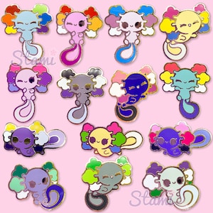 May include: A set of 12 axolotl pins featuring different pride flag colours. Each pin depicts a cartoon axolotl with a smiling face and a curled tail. The pins are made of metal and have a gold finish.