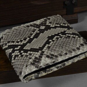 May include: A grey and black snakeskin wallet with a black leather trim.