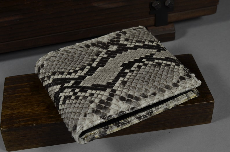 May include: A grey and black snakeskin wallet with a black leather trim.