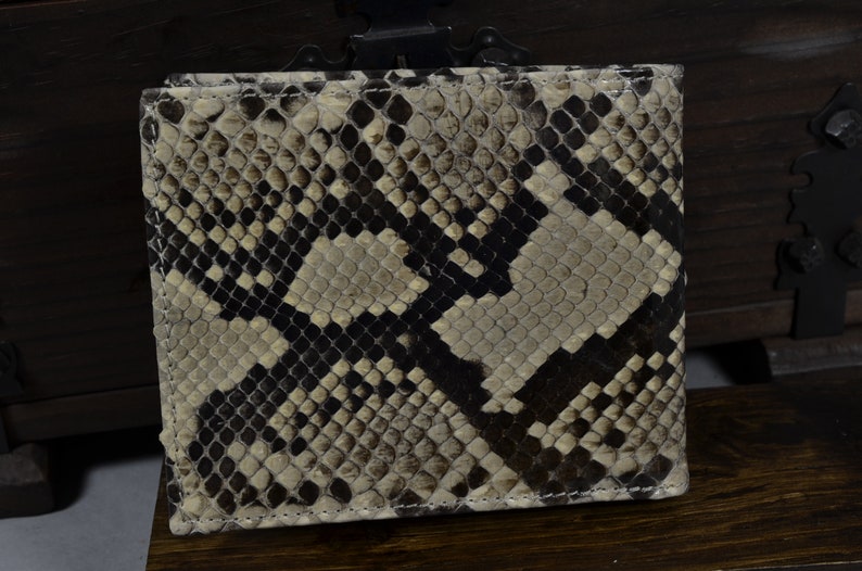 May include: A beige and brown snakeskin wallet with a stitched edge.