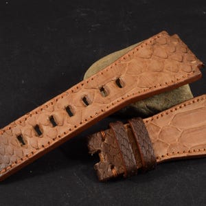 Op de afbeelding: Twee bruine leren horlogebandjes met een textuurpatroon. De bandjes zijn gemaakt van echt leer en hebben een gestikte rand.