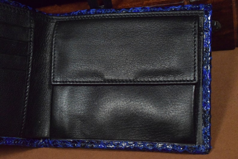 Peut inclure: Un portefeuille en cuir bleu avec un int&eacute;rieur noir et plusieurs emplacements pour cartes.