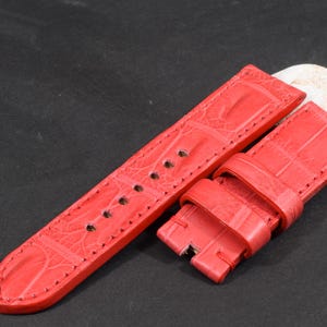 Op de afbeelding: Rood alligator horlogeband met een textuurpatroon. Het band is gemaakt van echt leer en heeft een gespsluiting.