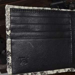 May include: A black leather wallet with multiple card slots and a billfold. The wallet is made of genuine snakeskin and has a subtle embossed logo on the front.